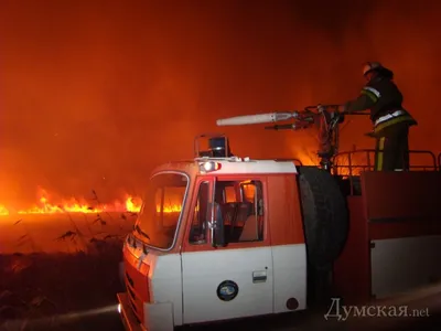 Пожарный в форме тушит пожар со шлангом на плечах | Премиум Фото