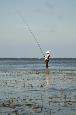 Рыбак с удочкой стоит на берегу реки | Премиум Фото