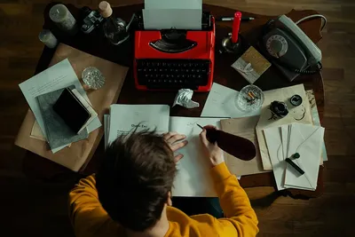 Писатель на работе Красивый молодой писатель сидя на таблице и писать  что-то в его Sketchpad Стоковое Изображение - изображение насчитывающей  почерк, дом: 101186993